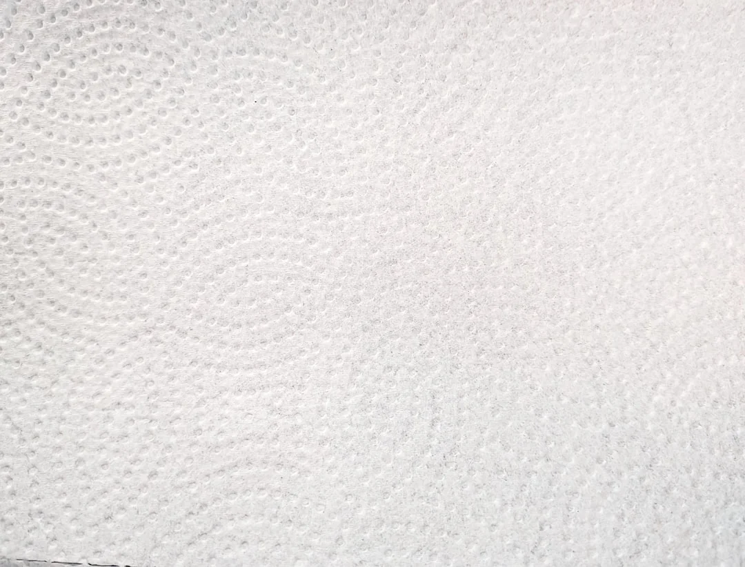 Close-up of hands wearing yellow gloves next to blue sponge on gray surface.